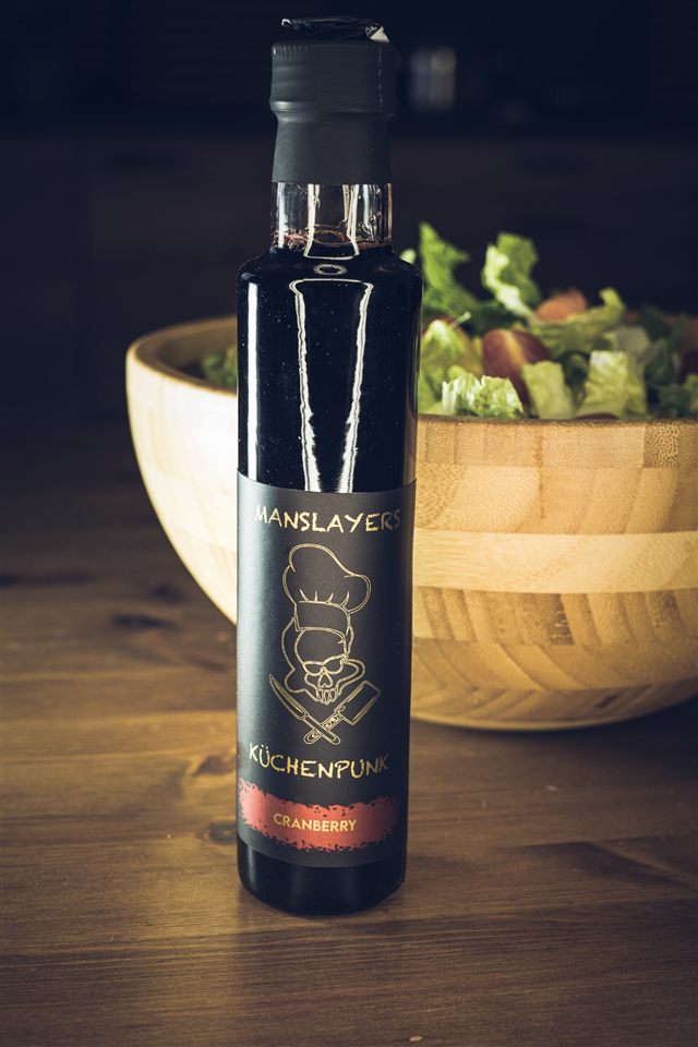 Manslayers Küchenpunk Cranberry — dunkle Flasche vor einer Salatschüssel