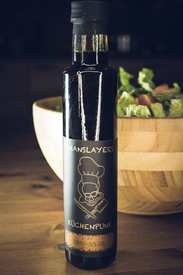 Manslayers Küchenpunk Feige-Dattel — dunkle Flasche vor einer Salatschüssel